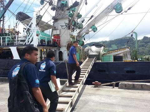 Fisheries observers carrying documents boarding a vessel 